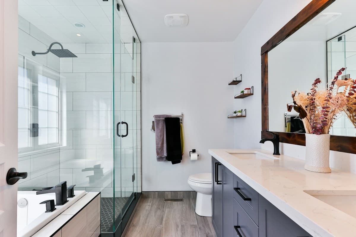 Real master bathroom with dual quartz vanity and frameless glass shower