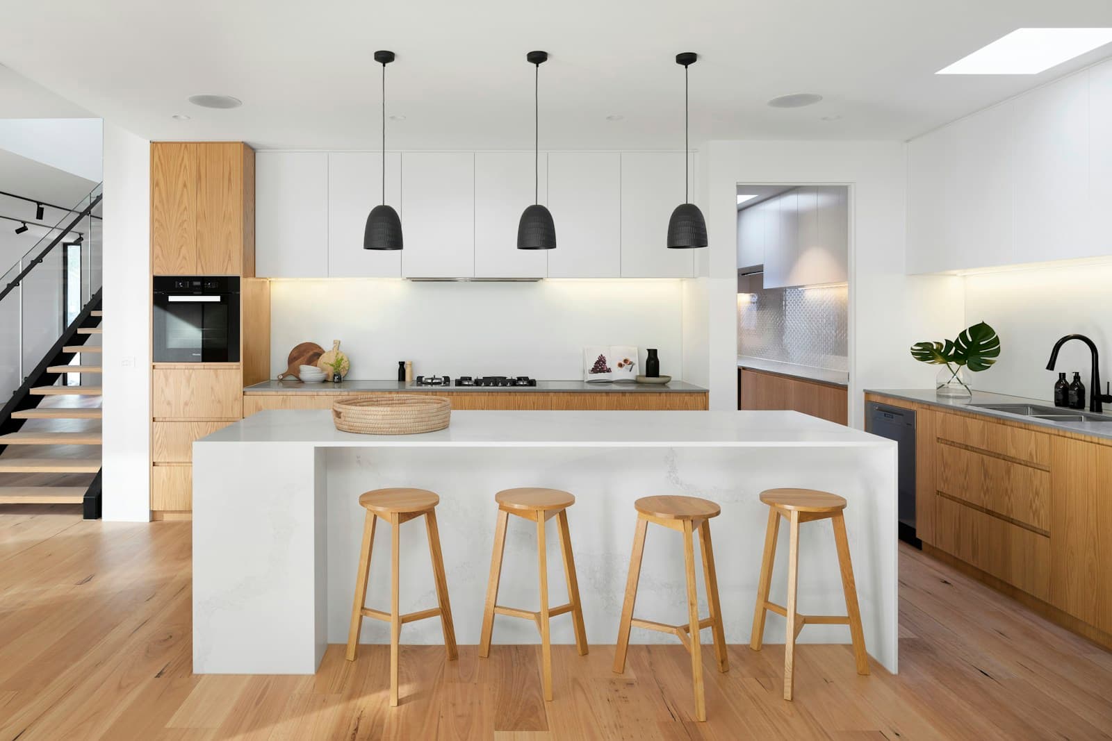 Real completed modern luxury kitchen with waterfall quartz island and natural oak cabinetry